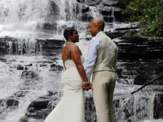 couple standing on rocks by waterfall