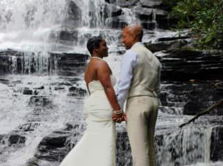 couple standing on rocks by waterfall