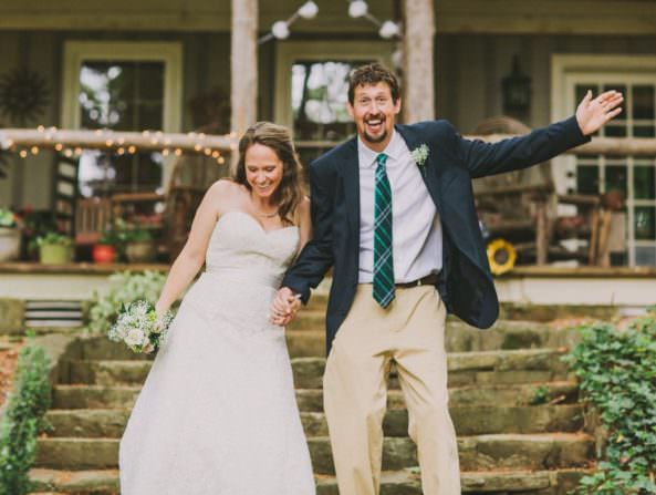 bride and groom smiling, with groom throwing out arm in joy