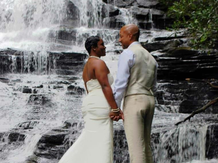 couple standing on rocks by waterfall