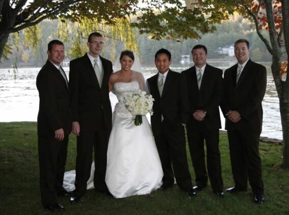 bride, groom and groomsmen on shore of lake