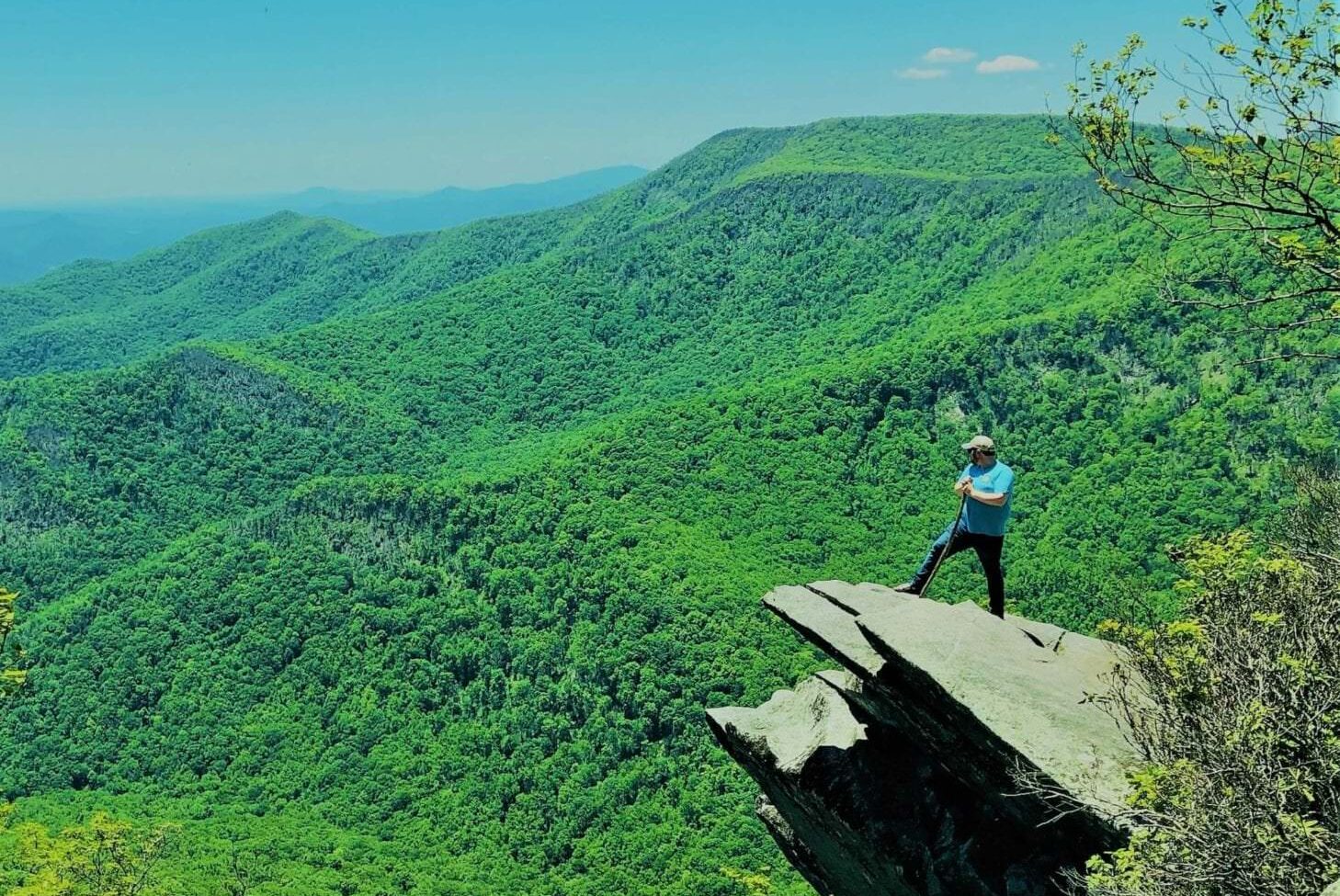 man standing on rock hiking through mountains